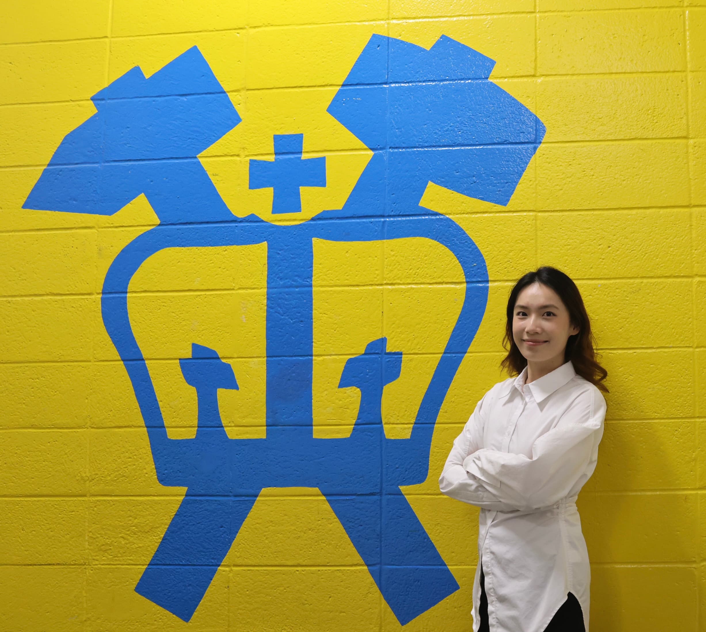 Siqi (Katy) Ye standing beside the Columbia University crown mural